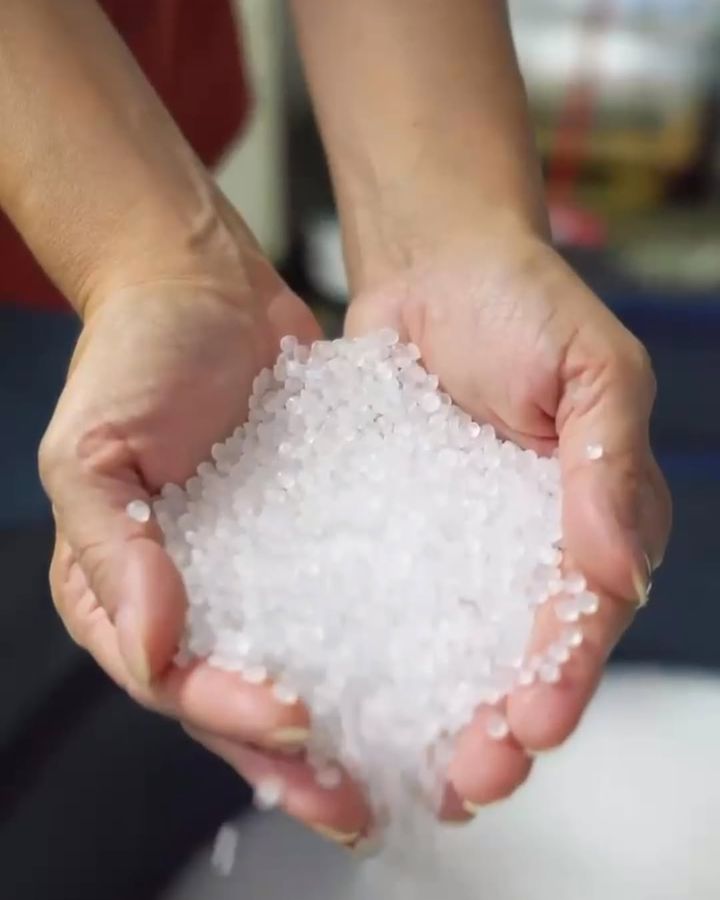 Mãos segurando grânulos de resina plástica