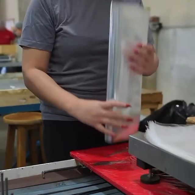Operadora conferindo uma embalagem plástica na linha de produção